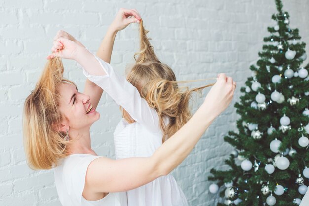 Zdjęcie mama i córka wygłupiają się na tle choinki