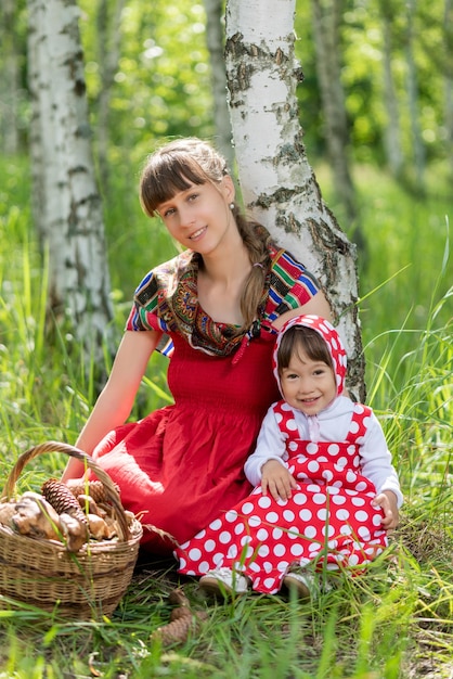 Zdjęcie mama i córka z koszem grzybów w lesie.