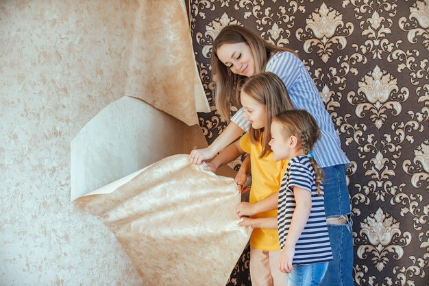 Mama i córki wspólnie usuwają starą tapetę ze ścian.