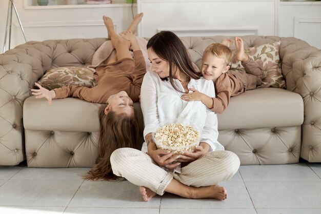 Mama I Dzieci Jedzą Popcorn W Domu W Dzień Wolny.