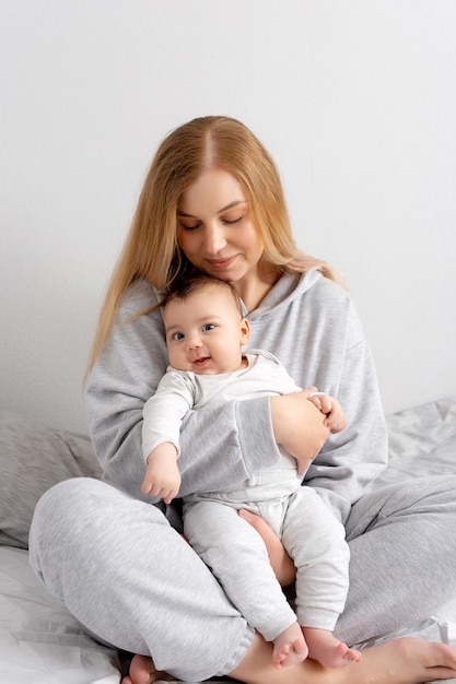 Mama i dziecko bawią się na łóżku Matka i syn szczęśliwa rodzina piękna blondynka i słodkie dziecko w domu