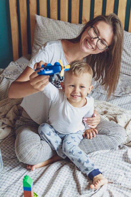 Mama i dziecko bawią się razem w sypialni na łóżku z plastikowymi klockami