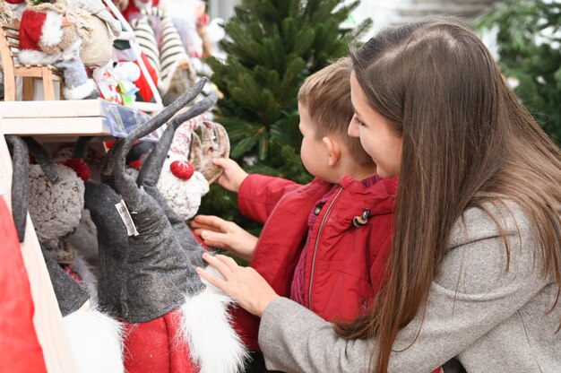 Mama i dziecko wybierają świąteczne zabawki na sklepowej półce podczas wakacji