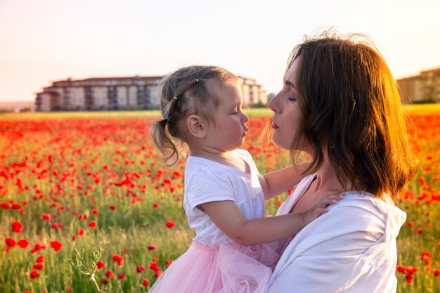 Mama i jej córeczka w białych ubraniach pozują na polu maku