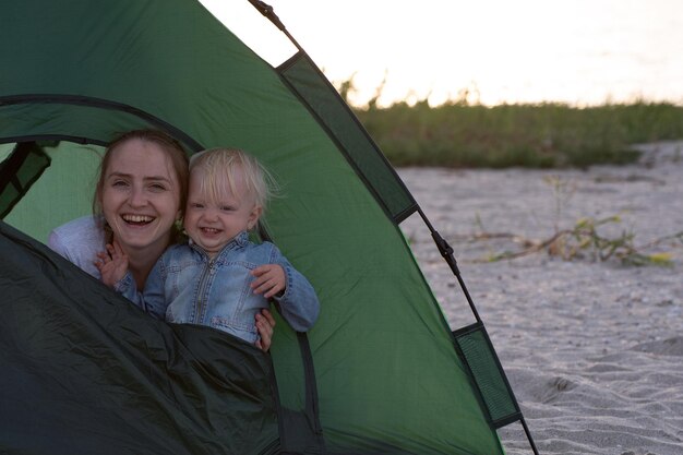 Mama i małe dziecko w namiocie na piaskowatym brzegu Camping z rodziną