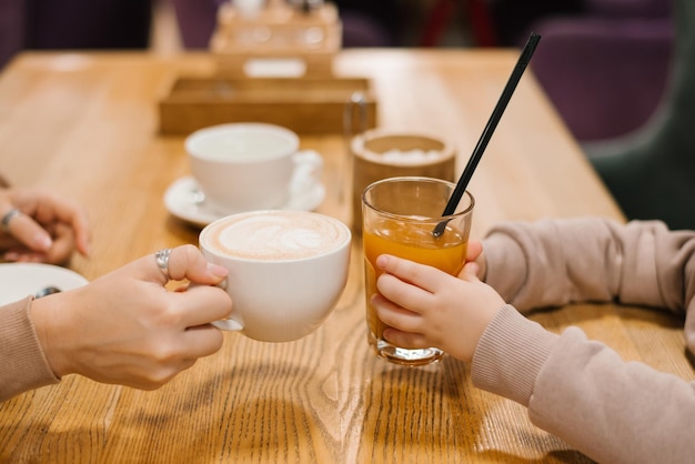 Mama I Syn Brzęczą Szklanki Z Filiżanką Kawy I Szklanką Soku Pomarańczowego Zbliżenie Rąk