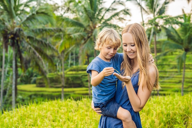 Mama i syn na polu ryżowym w tle tarasów ryżowych, Ubud, Bali, Indonezja. Podróżowanie z pojęciem dzieci. Nauczanie dzieci w praktyce