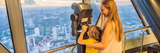 Mama i syn patrzą na panoramę miasta Kuala lumpur używają lornetki panoramiczny widok miasta Kuala lumpur