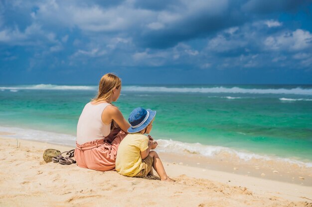 Mama i syn podróżujący na niesamowitej plaży Melasti z turkusową wodą, wyspa Bali Indonezja. Podróżowanie z koncepcją dzieci