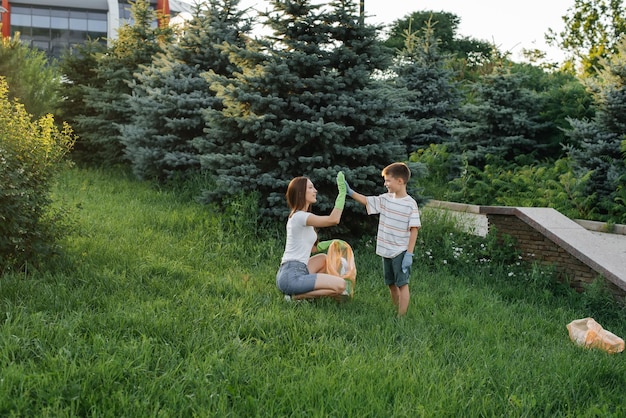 Mama i syn sprzątają śmieci w parku o zachodzie słońca Recykling odpadów w trosce o środowisko