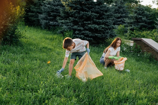 Mama i syn sprzątają śmieci w parku o zachodzie słońca Recykling odpadów w trosce o środowisko