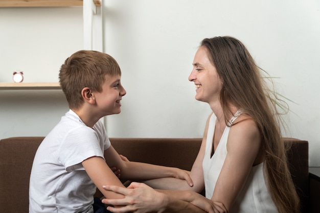 Mama i syn trzymają się za ręce i patrzą sobie w oczy. Dobre relacje z rodzicami.