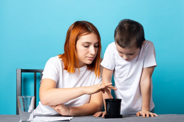 Mama I Syn Włożyli Ziemię Do Czarnego Garnka, Aby Posadzić Nasiona I Wyhodować Na Stole Roślinę Domową