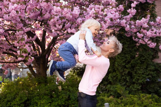 Mama i synek na łonie natury bawią się w wiosennym parku Mały chłopiec i mama dobrze się bawią podczas weekendowych zajęć w kwitnących ogrodach Sakura