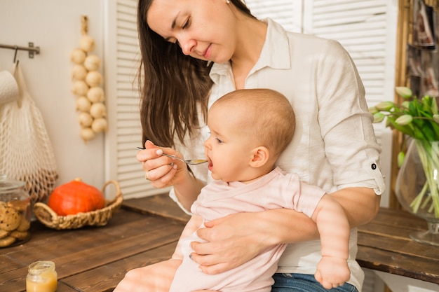 Mama karmi córkę łyżką w kuchni