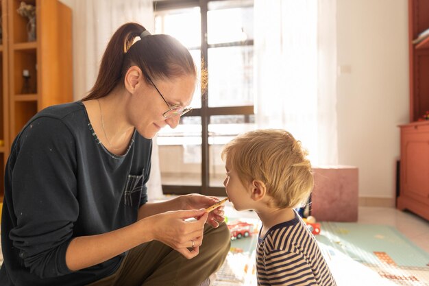 Mama karmi syna świeżo upieczonymi ciasteczkami w pokoju zabaw