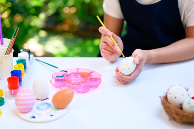 Mama koloruje jajka na obchody Wielkanocy w kwietniu. Przygotowanie i malowanie do dekoracji domu rodzinnego.