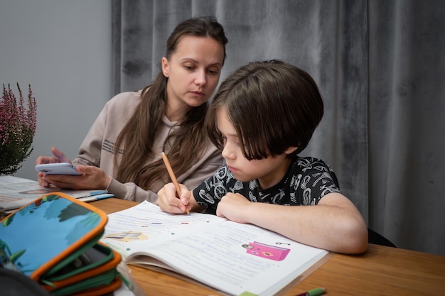 Mama patrzy, jak jej dziecko robi zadanie domowe Mama uczy się z synem w domu Szkoła domowa