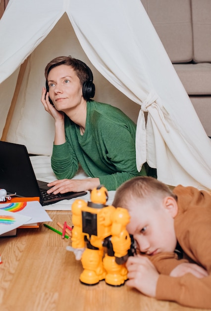 Mama pracuje na laptopie słuchawki dziecko gra następnie