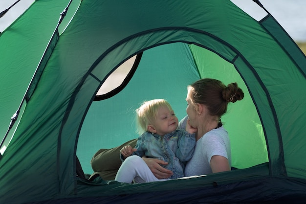 Mama Przytula Dziecko Leżąc W Namiocie. Odpoczynek Na Kempingu. Turystyka, Podróże, Zajęcia Na świeżym Powietrzu.