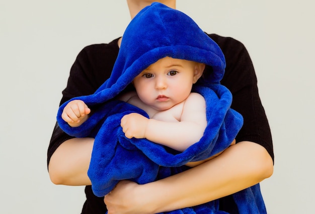 Mama przytula swoje maleństwo przykryte niebieskim ręcznikiem. Matka z dzieckiem po kąpieli