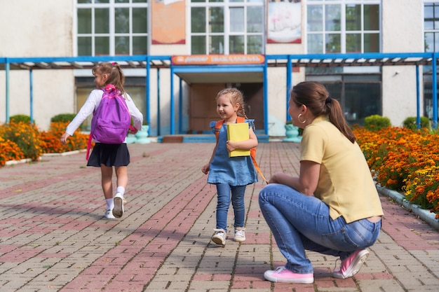 Mama spotyka córkę ze szkoły podstawowej. dziecko wpada w ramiona swojej matki.