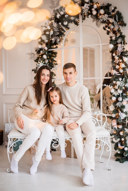 Mama, tata i córka na Boże Narodzenie. Portret rodziny na tle sylwestrowym