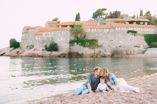 Mama, Tata I Ich Synek Leżący Nad Brzegiem Morza Na Tle Wyspy Sveti Stefan