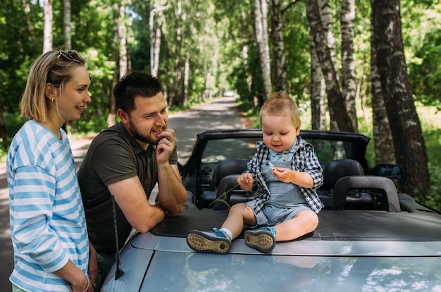 Zdjęcie mama, tata i mały syn w kabriolecie, letnia rodzinna wycieczka na przyrodę.