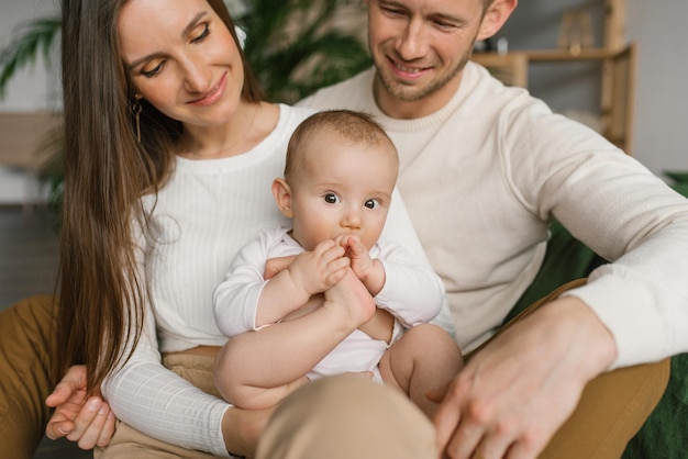 Mama tata i sześciomiesięczny synek w ramionach spędzają razem czas w swoim przytulnym domu