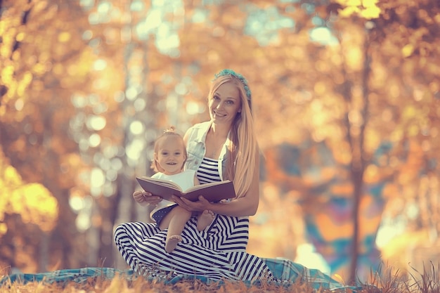 Mama trzyma córkę w ramionach jesienne zdjęcia w żółtym parku