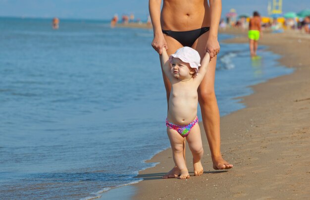 Mama uczy córkę chodzić na plażę.