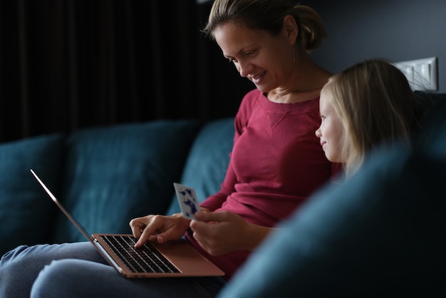 Mama z dzieckiem na kanapie płaci za zakupy online