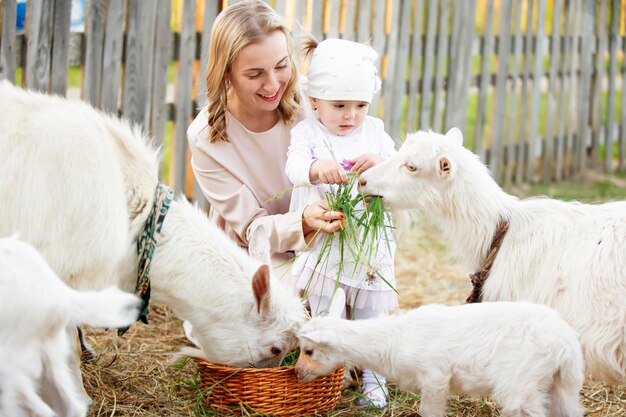 Mama z małą córeczką karmi kozę