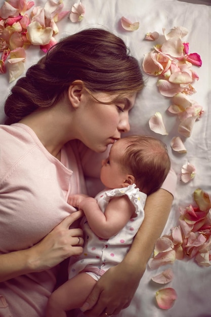 Mama z małą nowo narodzoną córką leżącą na łóżku w sypialni