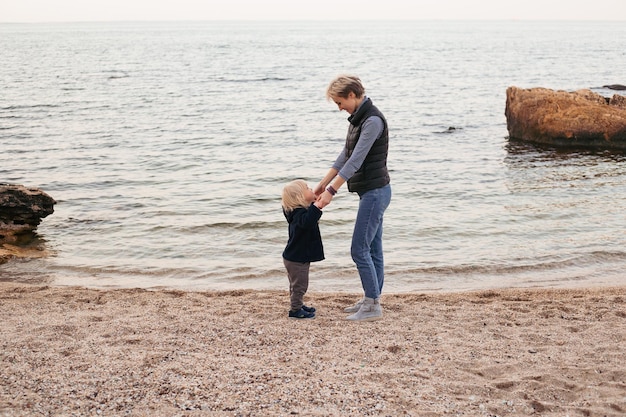 Mama z małym synem na plaży w pobliżu morza w okresie jesiennym