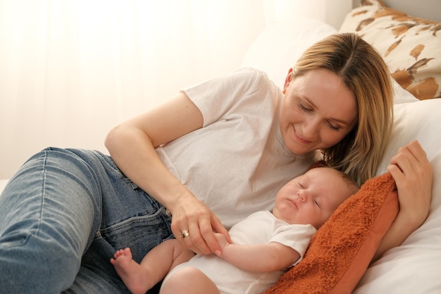 Mama z noworodkiem leży na łóżku mama całuje dziecko mamusia miłość