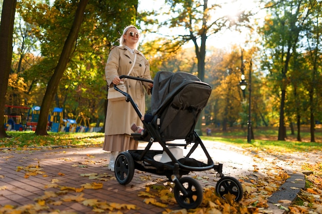 Mama z wózkiem spaceruje po parku