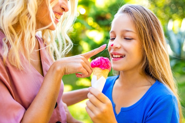 Mama ze swoim dzieckiem jedząc lody w parku i uśmiechając się na tropikalnej plaży