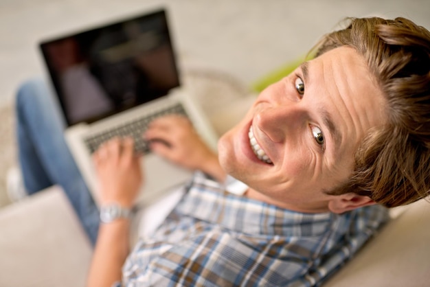 Zdjęcie man portrait and laptop on sofa for online as freelance journalist for report research connectivity or networking male person above and internet for remote work in london communication or web