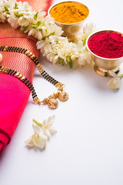 Mangalsutra lub złoty naszyjnik do noszenia przez zamężne hinduskie kobiety, ułożony z tradycyjnym sari z huldi kumkum i kwiatami mogra gajra, selektywne skupienie