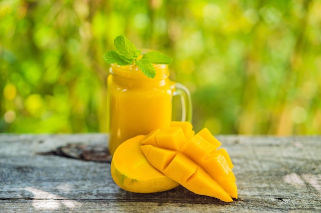 Mango smoothie w szklanym słoiku Mason i mango na starym drewnianym tle Mango shake Koncepcja owoców tropikalnych