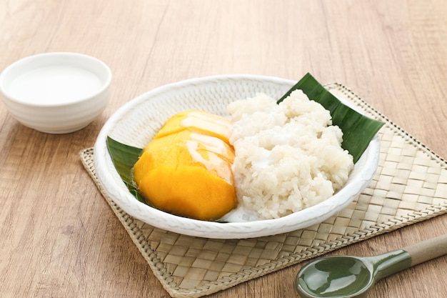 Mango z kleistym ryżem, tajski deser. Podawany w białym talerzu na drewnianym tle
