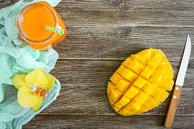 Zdjęcie mangowy smoothie w szklanym słoju świeżym mango na drewnianym tle i. shake z mango koncepcja owoców tropikalnych. widok z góry