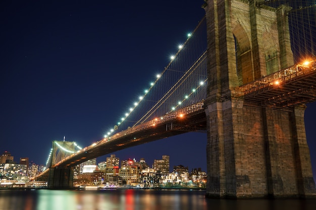 Zdjęcie manhattan bridge i brooklyn skyline z ładnym niewyraźnym odbiciem w rzece w nocy