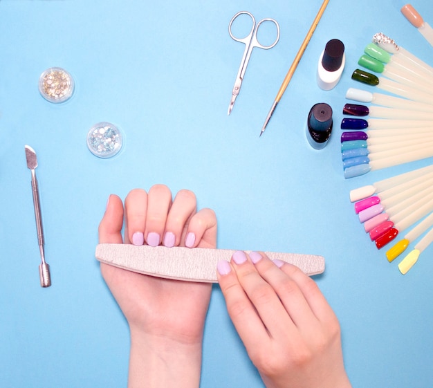 Manicure - narzędzia do tworzenia, lakiery żelowe, pielęgnacja i higiena paznokci. Salon kosmetyczny, salon paznokci, mastira do pracy z nochtami. Niebieskie tło
