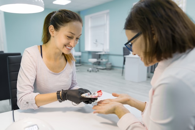 Manikiurzystka kosmetyczki rozmawia z klientką, robi manicure