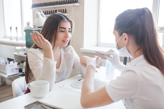 Manikiurzystka robi manicure w salonie. Mistrz obsługujący swojego klienta. Procedura pielęgnacji paznokci.