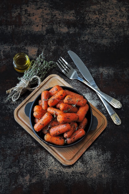 Zdjęcie marchewki zapiekane z ziołami na żeliwnej patelni.
