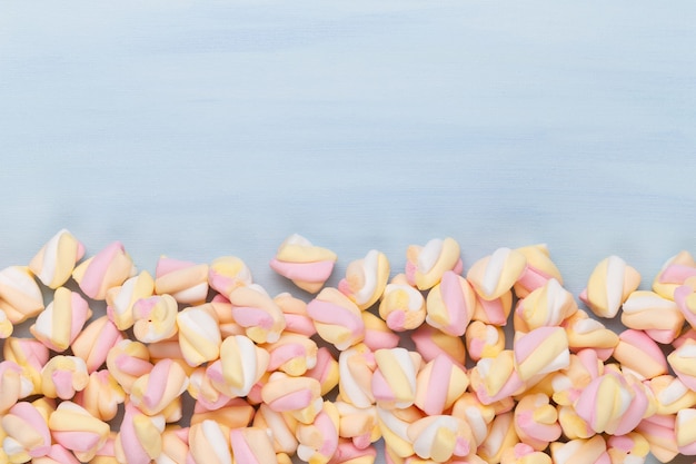 Marshmallows na niebieskim stole z lato. Widok płaski lub górny. Tło lub tekstura kolorowych mini marshmallows.